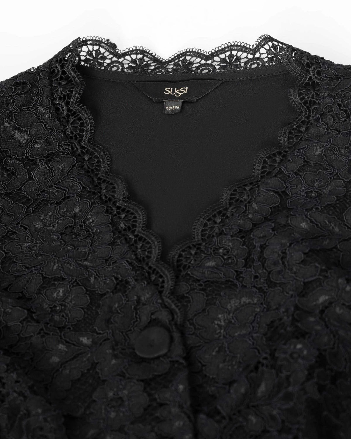 Floral lace follows the neckline in a scalloped edge beside the front fastening.