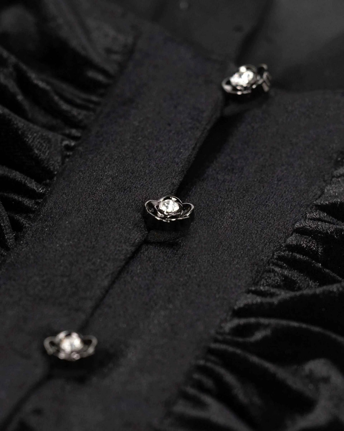Small bright buttons run beside narrow gathered velvet sections, creating a repeated vertical detail.