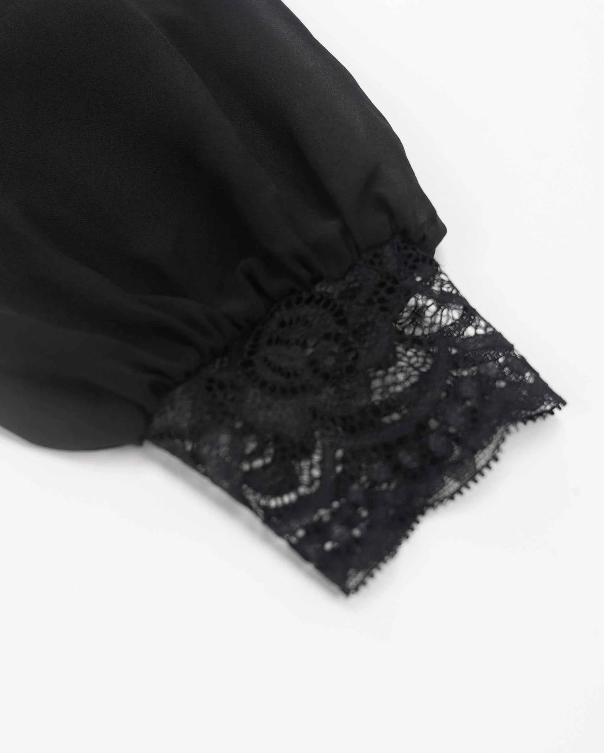 The sleeve gathers above a broad lace cuff, introducing a change from smooth fabric to open floral texture.