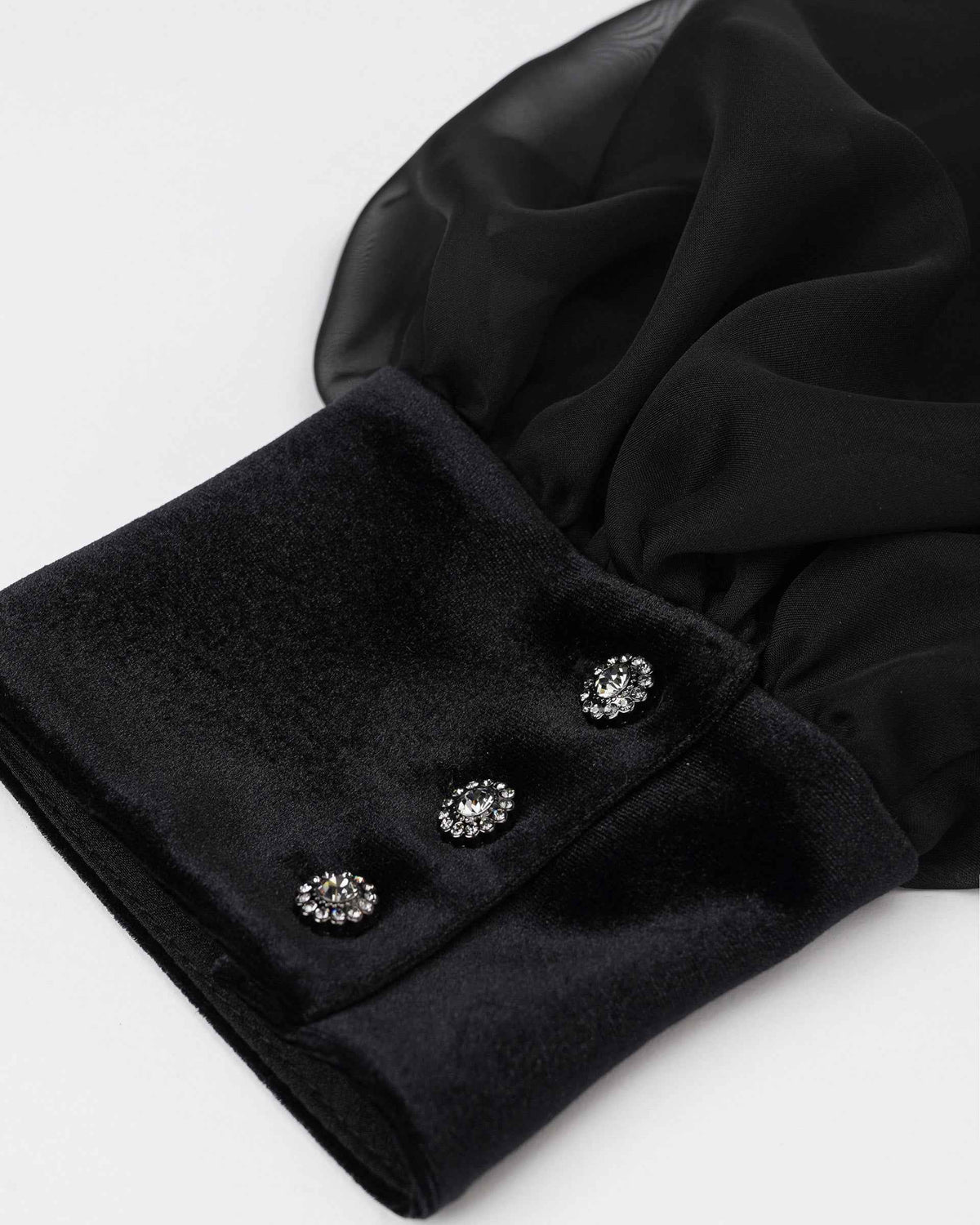 The sheer sleeve gathers into a solid black cuff finished with decorative buttons.