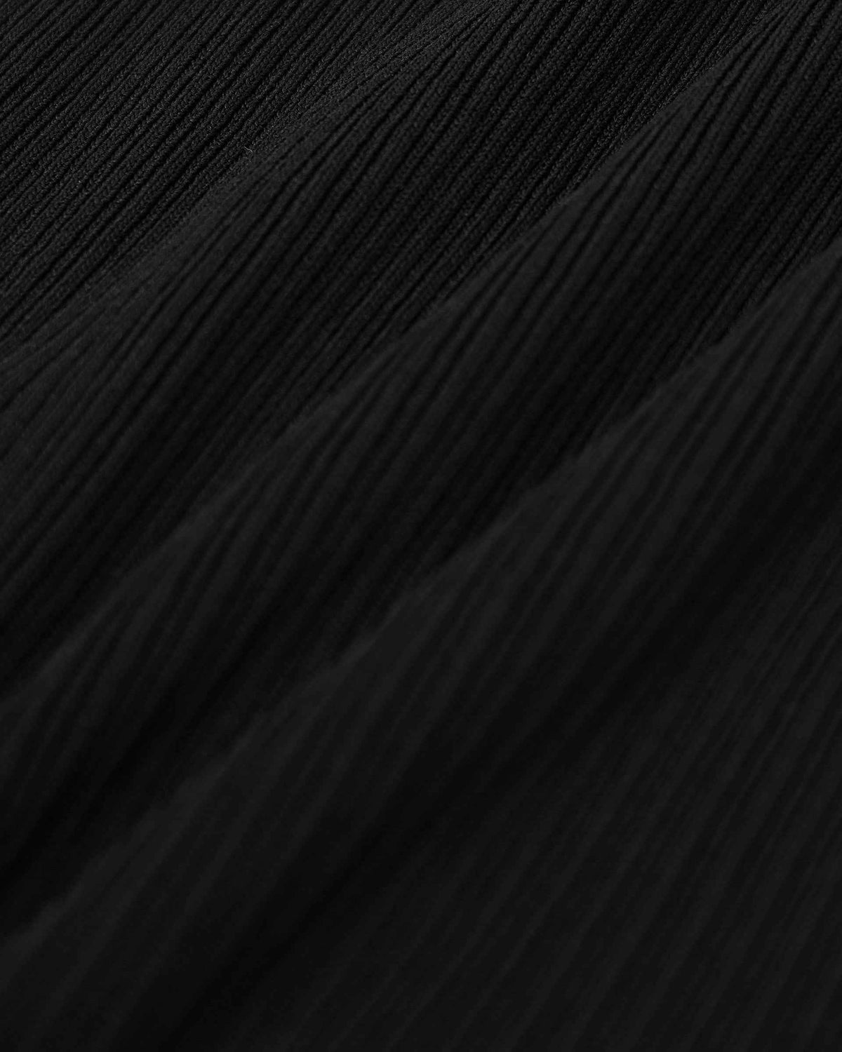 Narrow ribs travel vertically through the black knit, adding texture without introducing another colour.