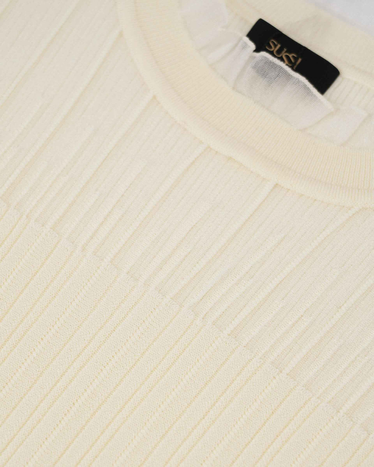 A delicate, lightly ruffled border follows the ivory neckline above the ribbed body.