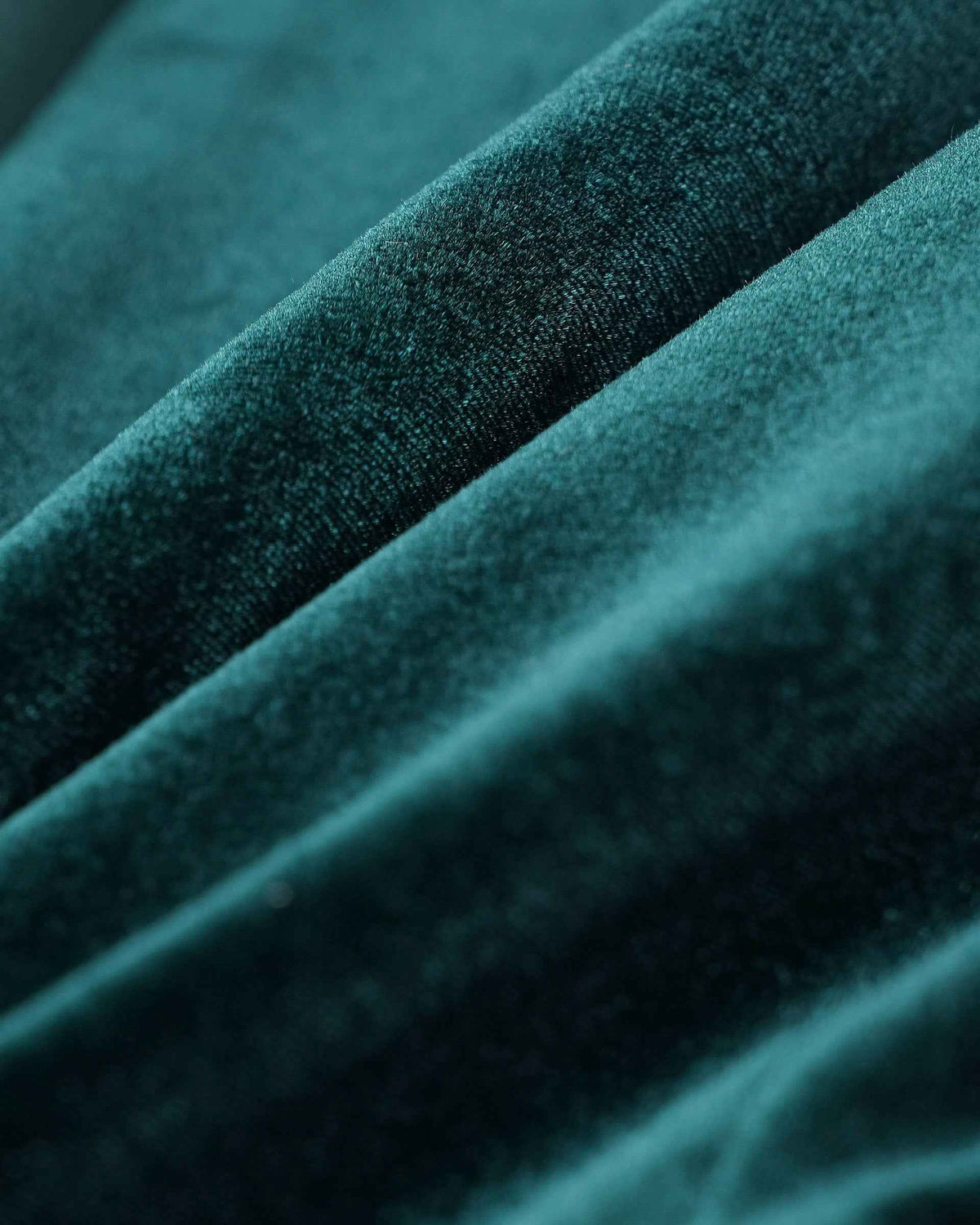 Close-up of dark green velvet showing fine pile and contrasting highlights along the folds.