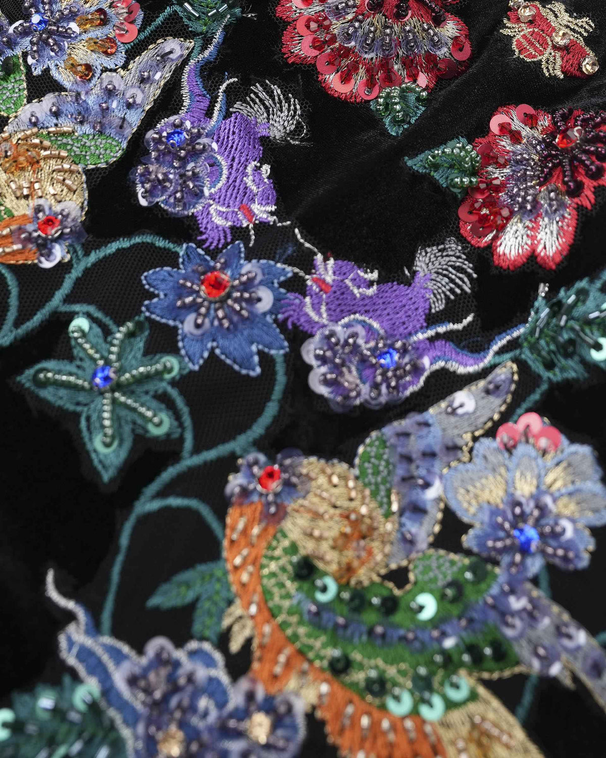 Blue, purple, and red floral details stand out against the dark fabric, with small reflective accents among the threads.