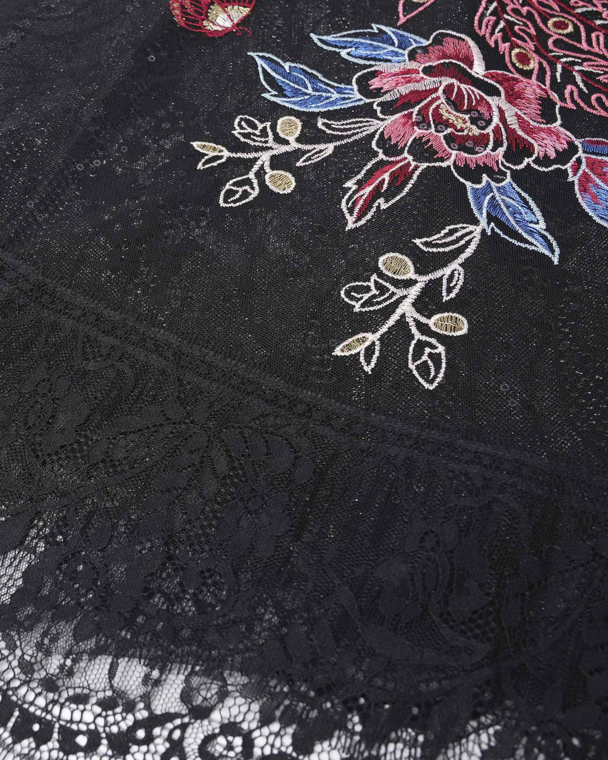 Colourful embroidery sits above a fine lace border on the dark fabric.