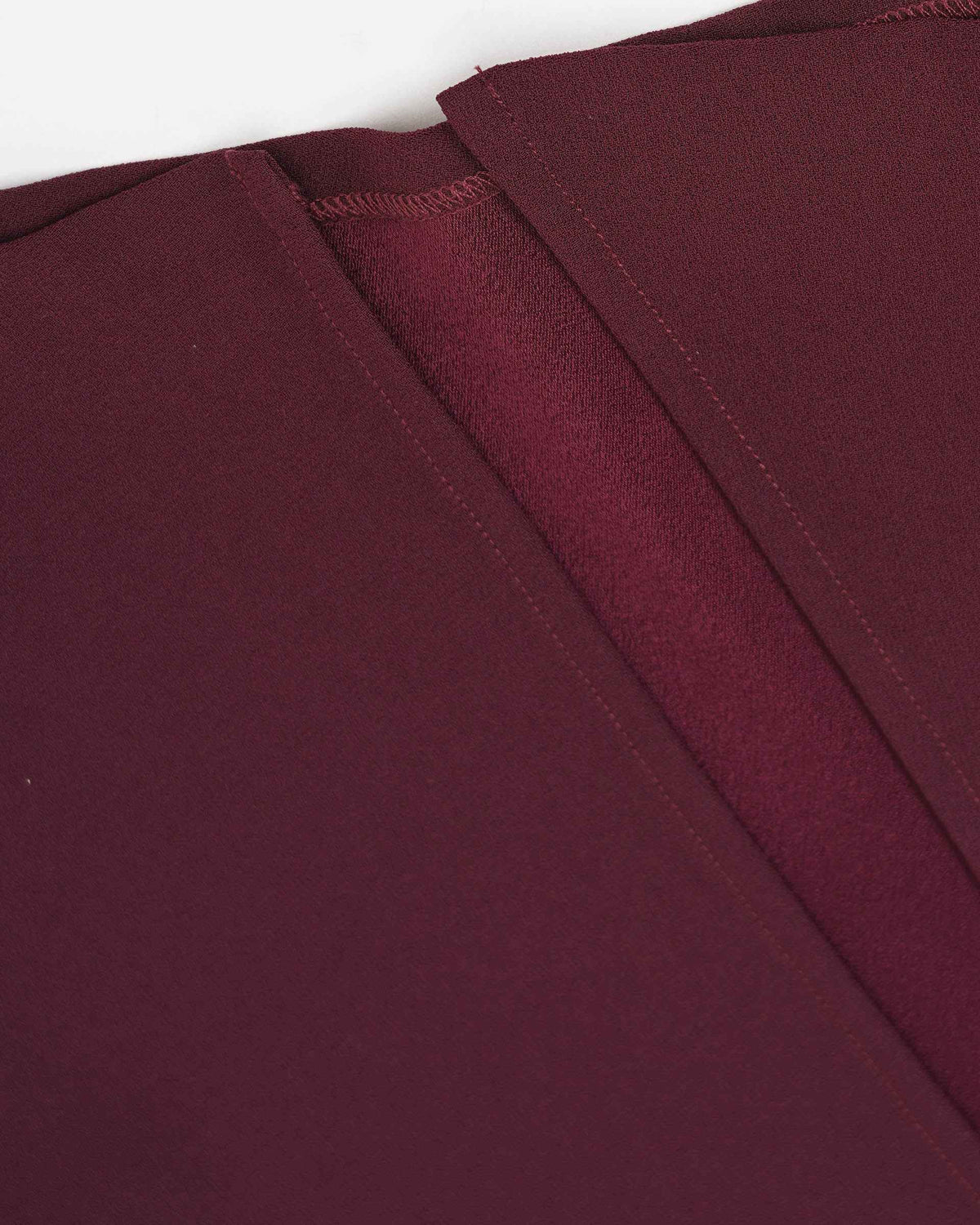 The close-up reveals a neat seam and fastening area in the burgundy fabric.