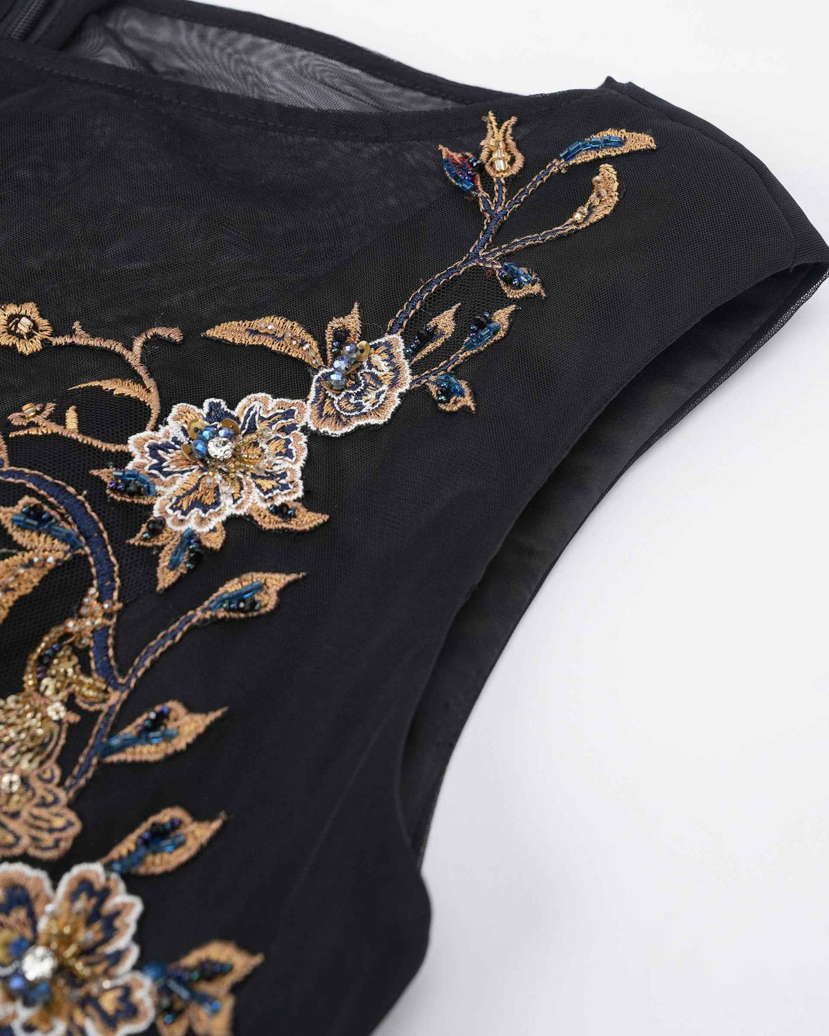 Embroidered flowers follow the edge of the sheer neckline, creating a decorative frame around its transparency.