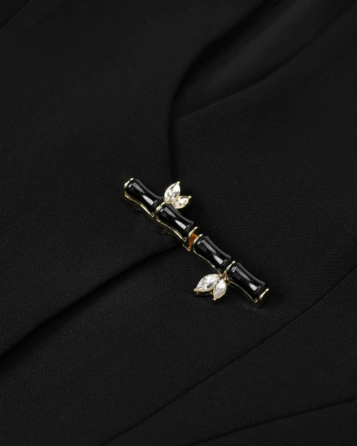 A dark segmented clasp with small leaf-like accents bridges the blazer's front.