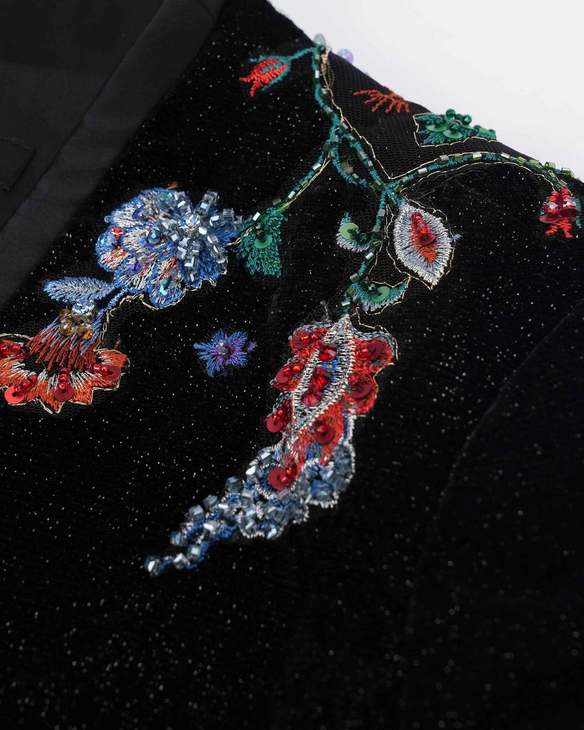 Colourful flowers and curved stems sit against the dark velvet, with blue and red accents lifting the motif.
