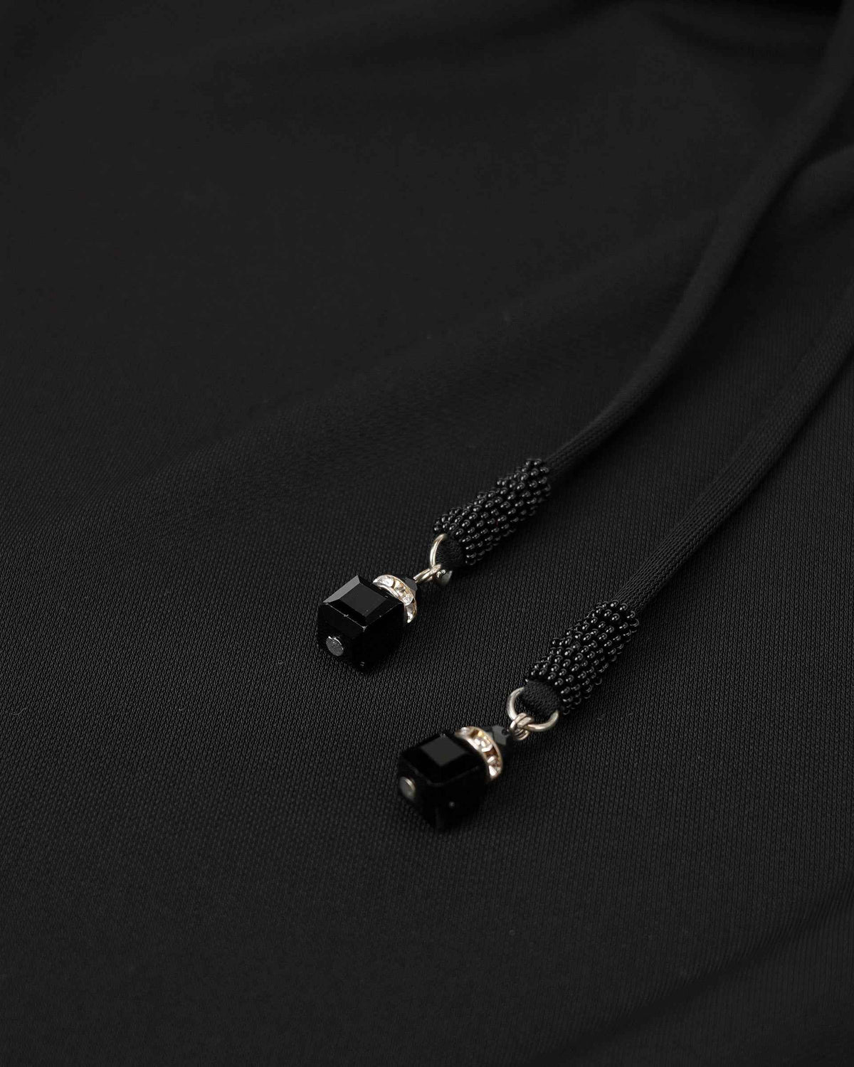 Dark cords end in small decorative tips beside the skirt's gathered fabric.