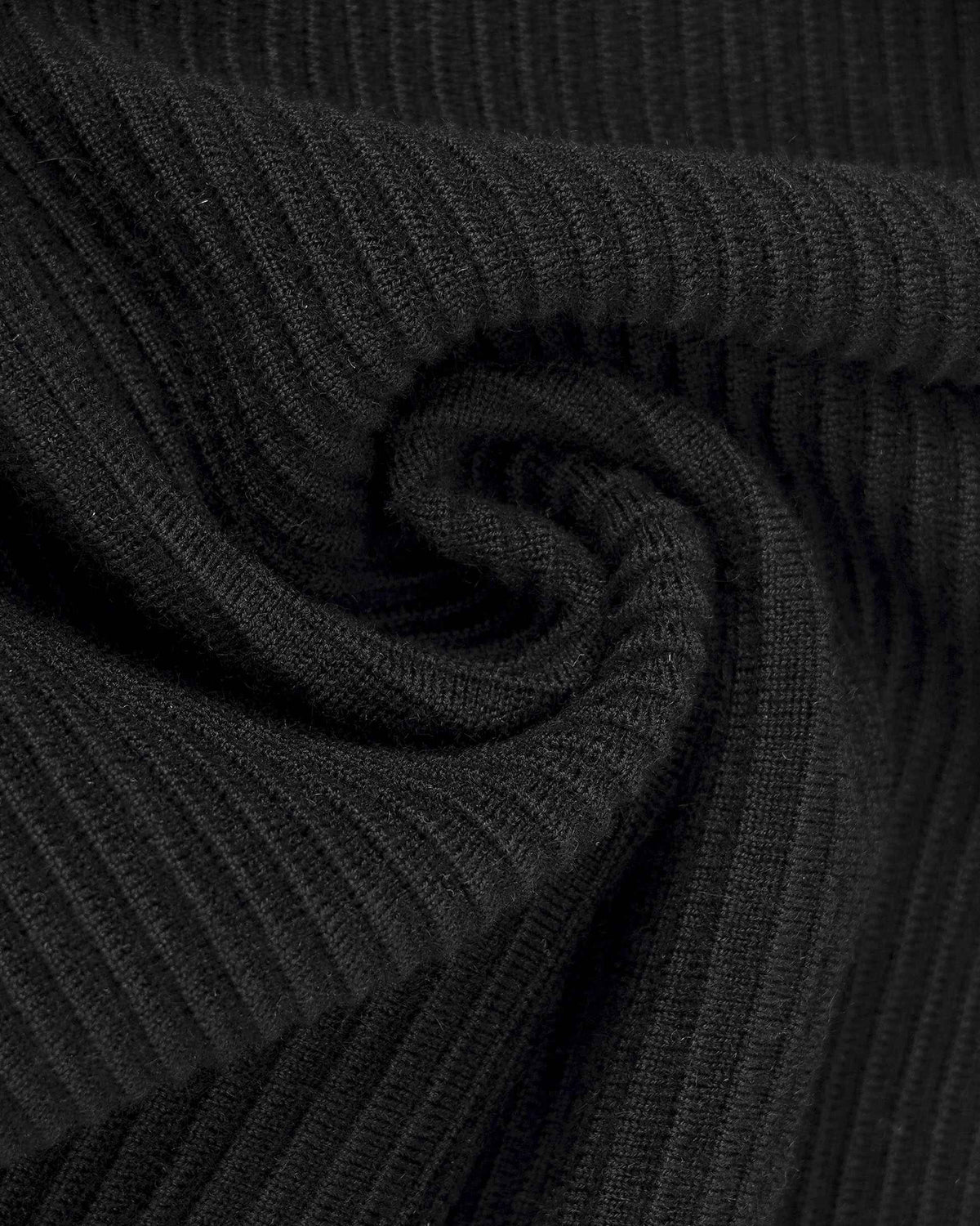 Closely spaced ribs run across the black knit, becoming more pronounced where the fabric folds.