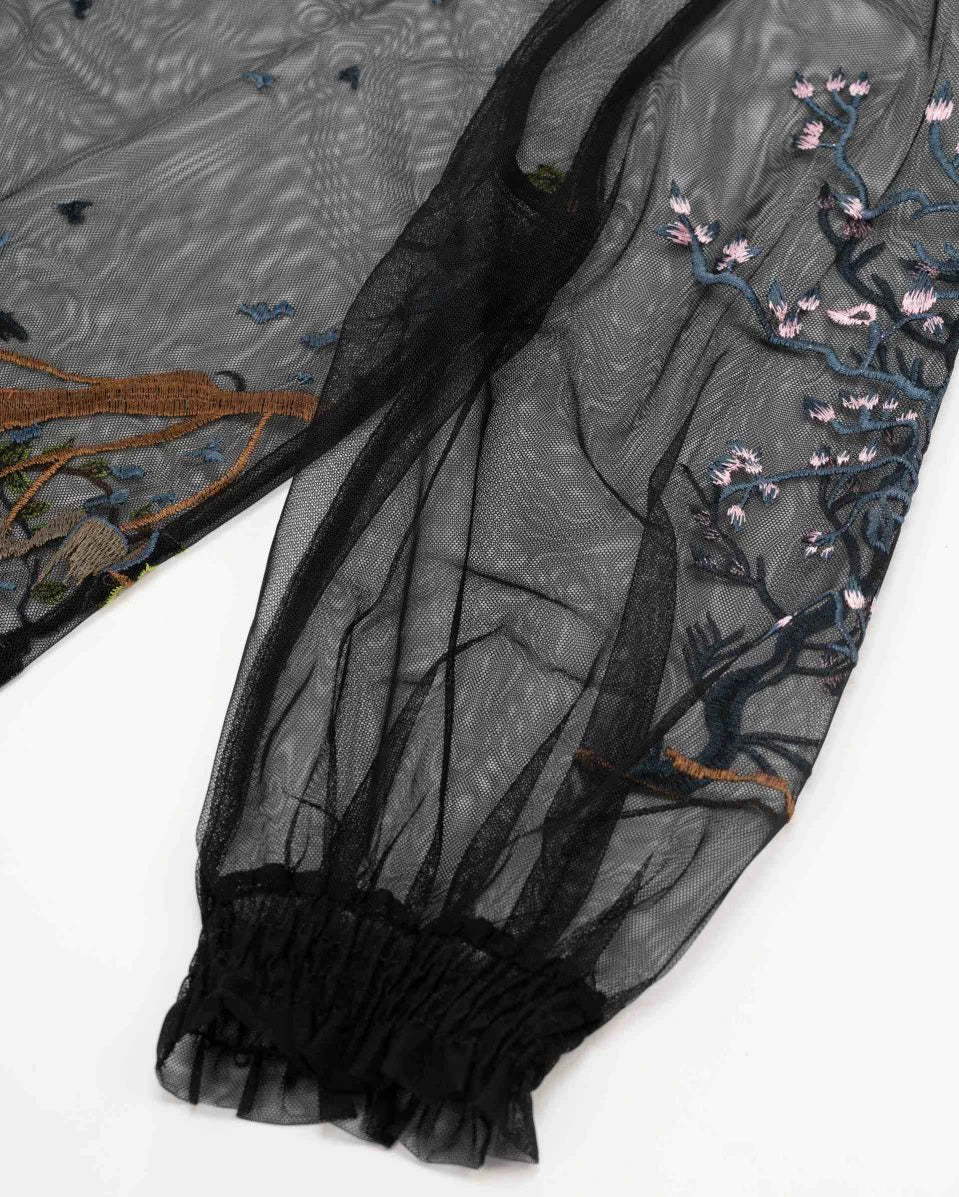 The embroidered transparent sleeve narrows into a closely gathered cuff, making the fuller shape above more apparent.