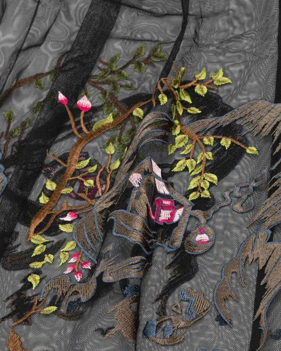 Embroidered branches, small blossoms and landscape details extend across the transparent dark layer.