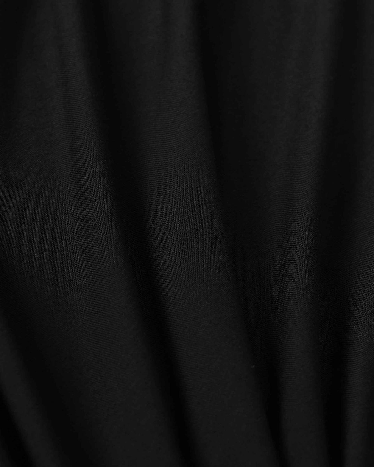 Long folds pass through the black fabric, creating soft changes of light across the surface.