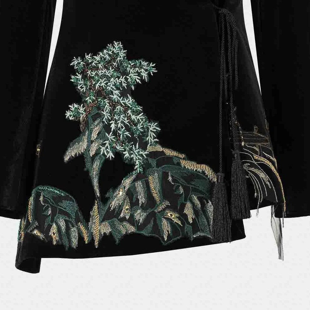 Green foliage and pale landscape details gather near the blazer's lower front.