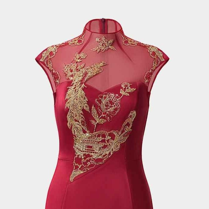 Gold-toned embroidery decorates the upper front of the red gown, creating a strong contrast with its plain skirt.