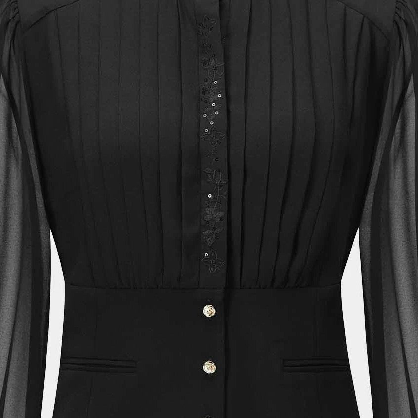 Fine folds travel down the blouse's upper front before meeting a more fitted lower section.